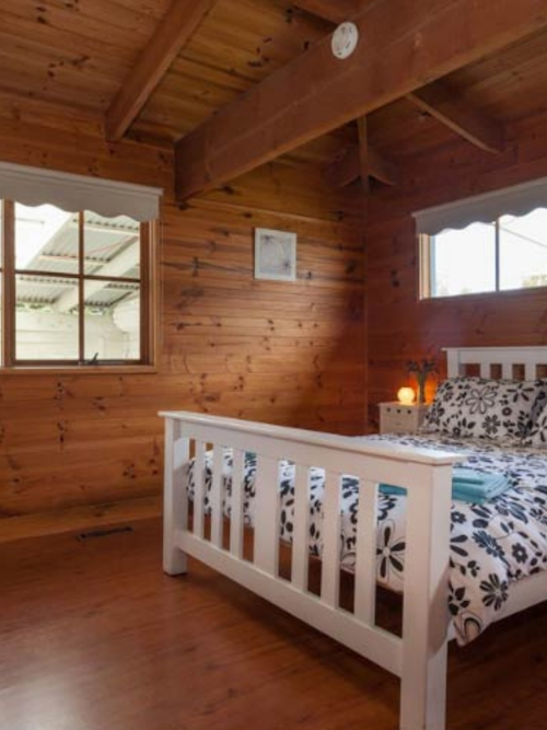 timber room with queen sized bed and white headboard