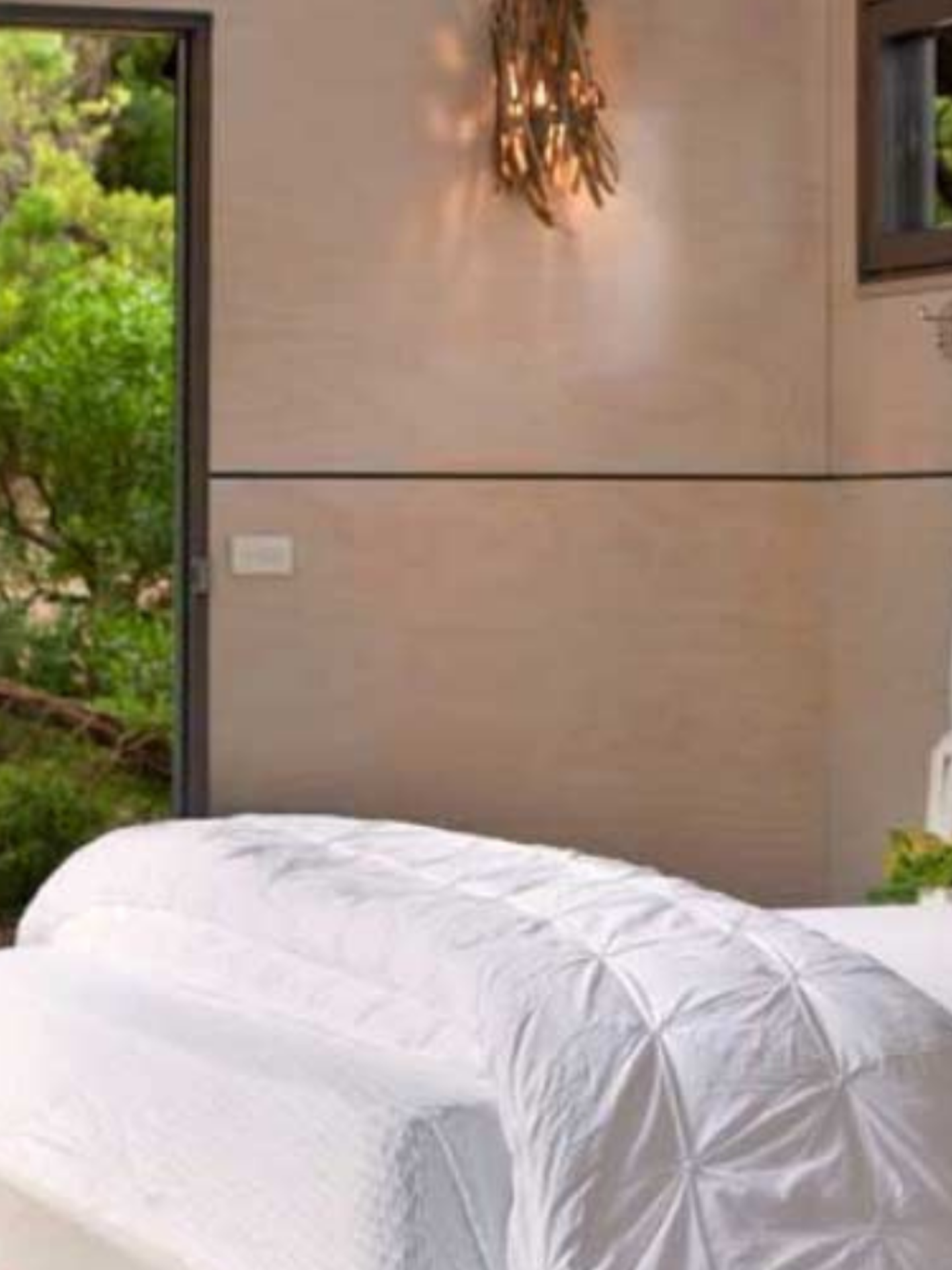 hotel bed with door open to show nature outside