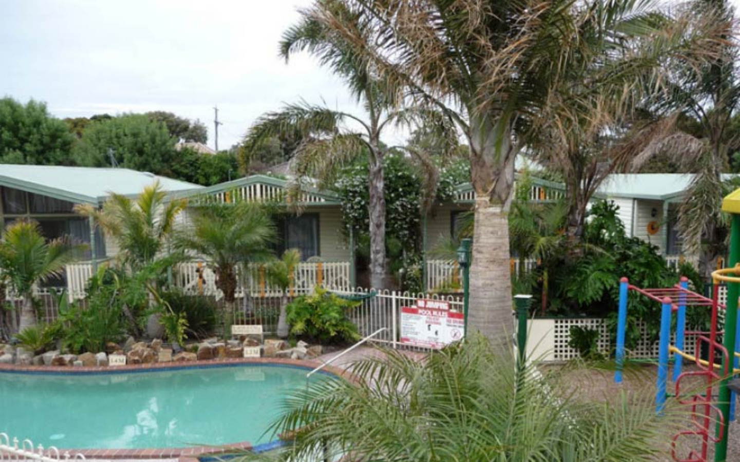 inground pool with playground and palm tree