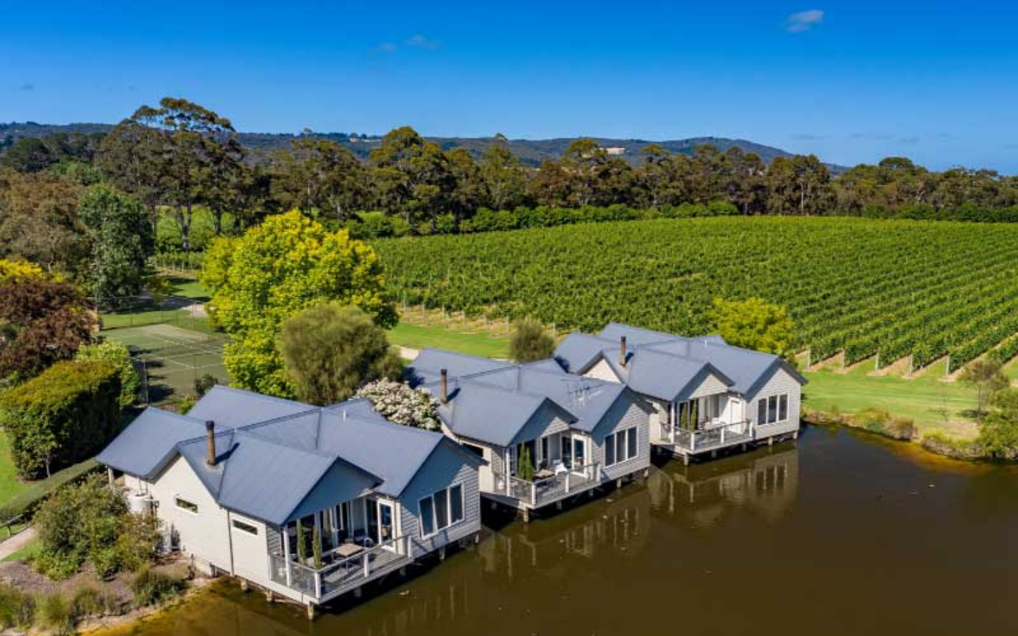 villas sitting on lake with vineyards in the background