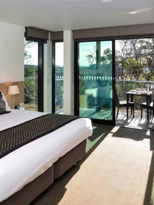 modern hotel room with bed and balcony with outdoor setting
