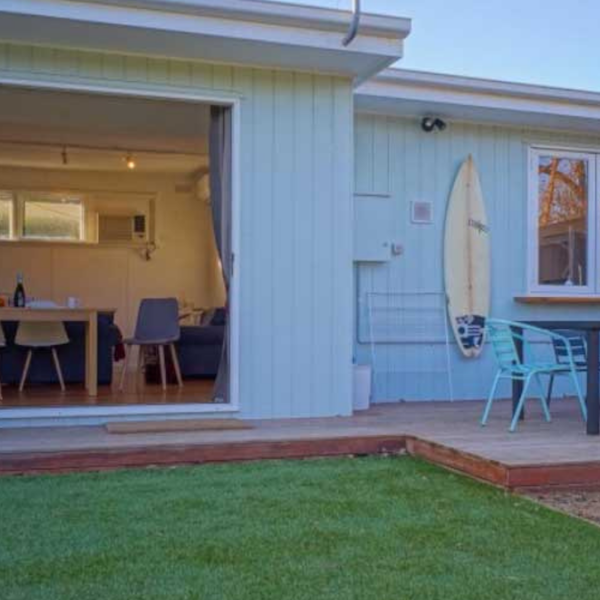 white cottage behind green lawn and outdoor patio set