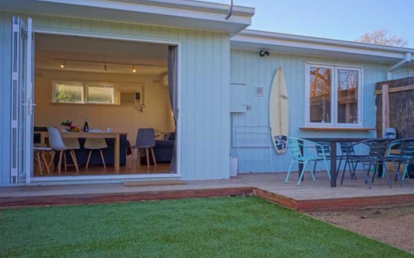 white cottage behind green lawn and outdoor patio set