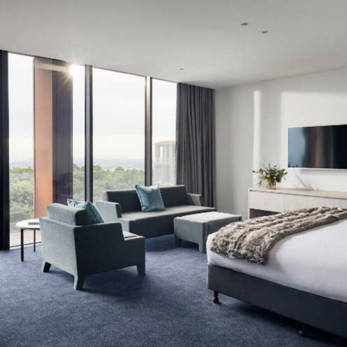 modern hotel suite with bed, lounge & dining areas with stunning views