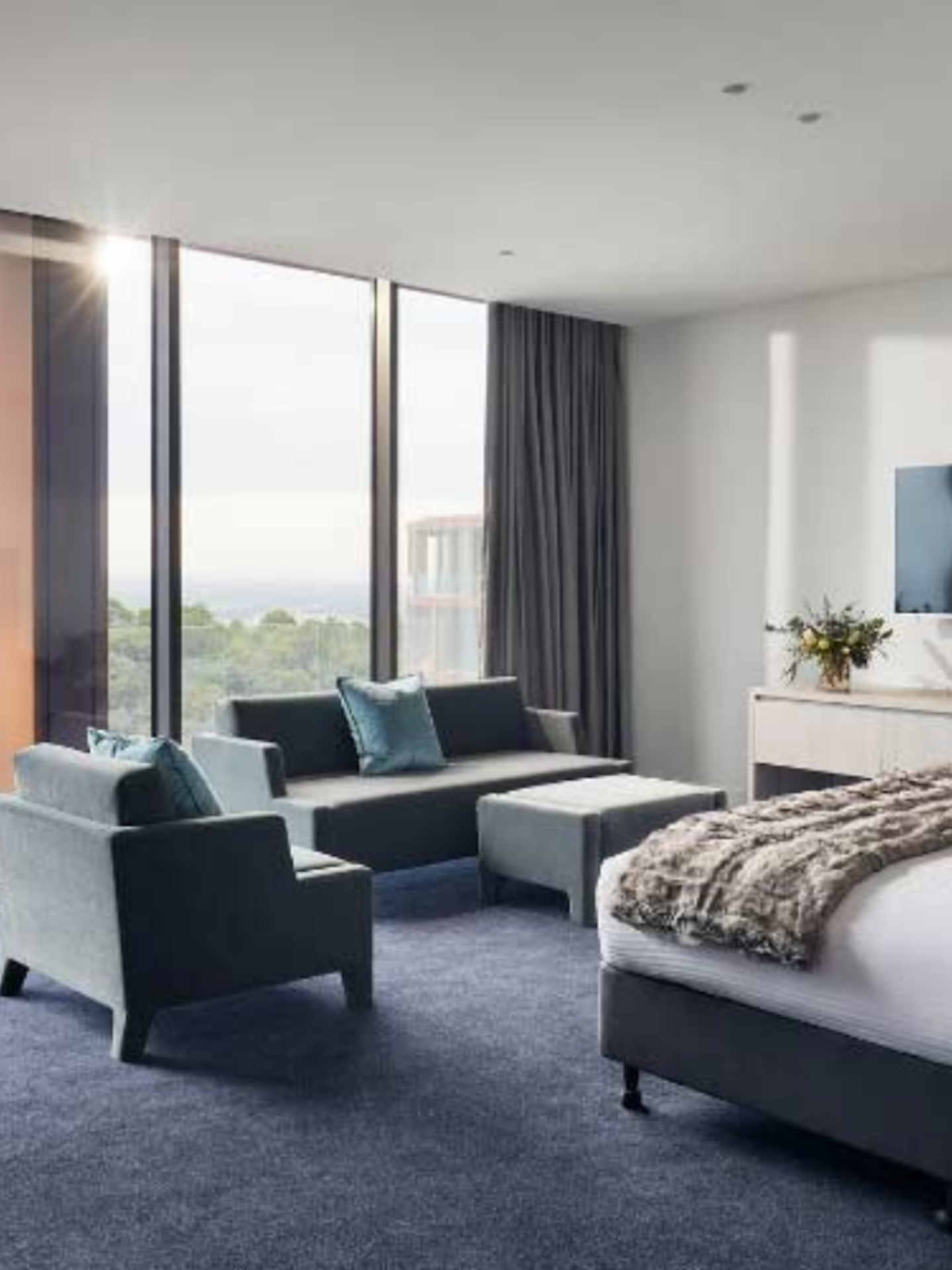 modern hotel suite with bed, lounge & dining areas with stunning views