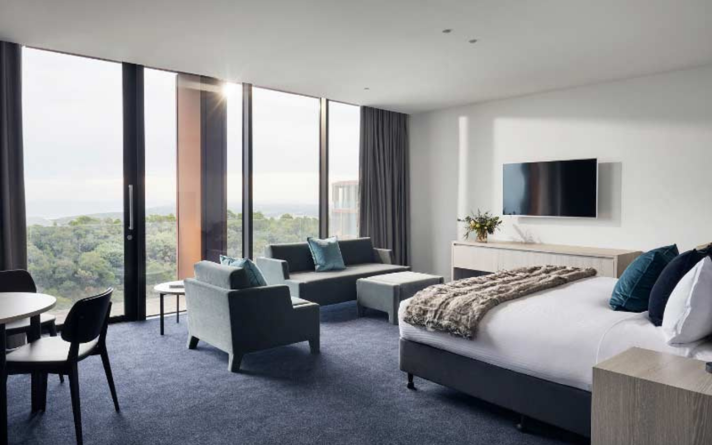 modern hotel suite with bed, lounge & dining areas with stunning views
