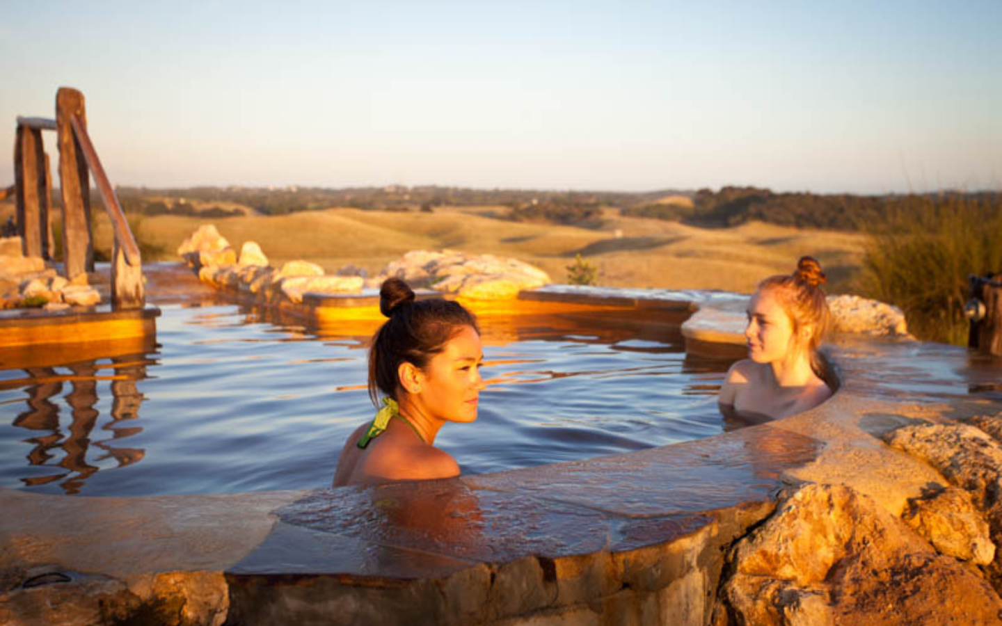 two girls sitting in a pool at dusk