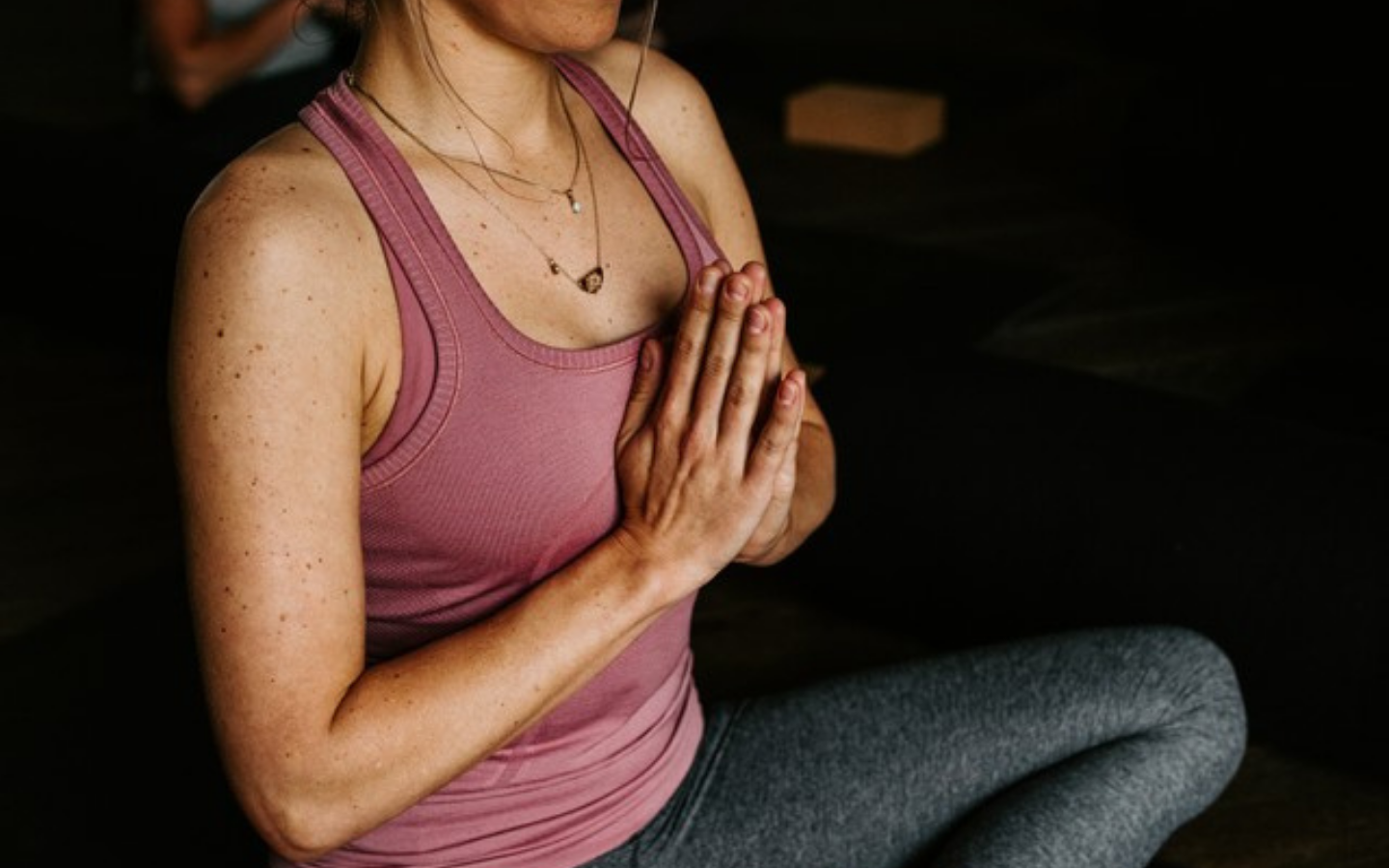 woman with hands in prayer sitting cross legged