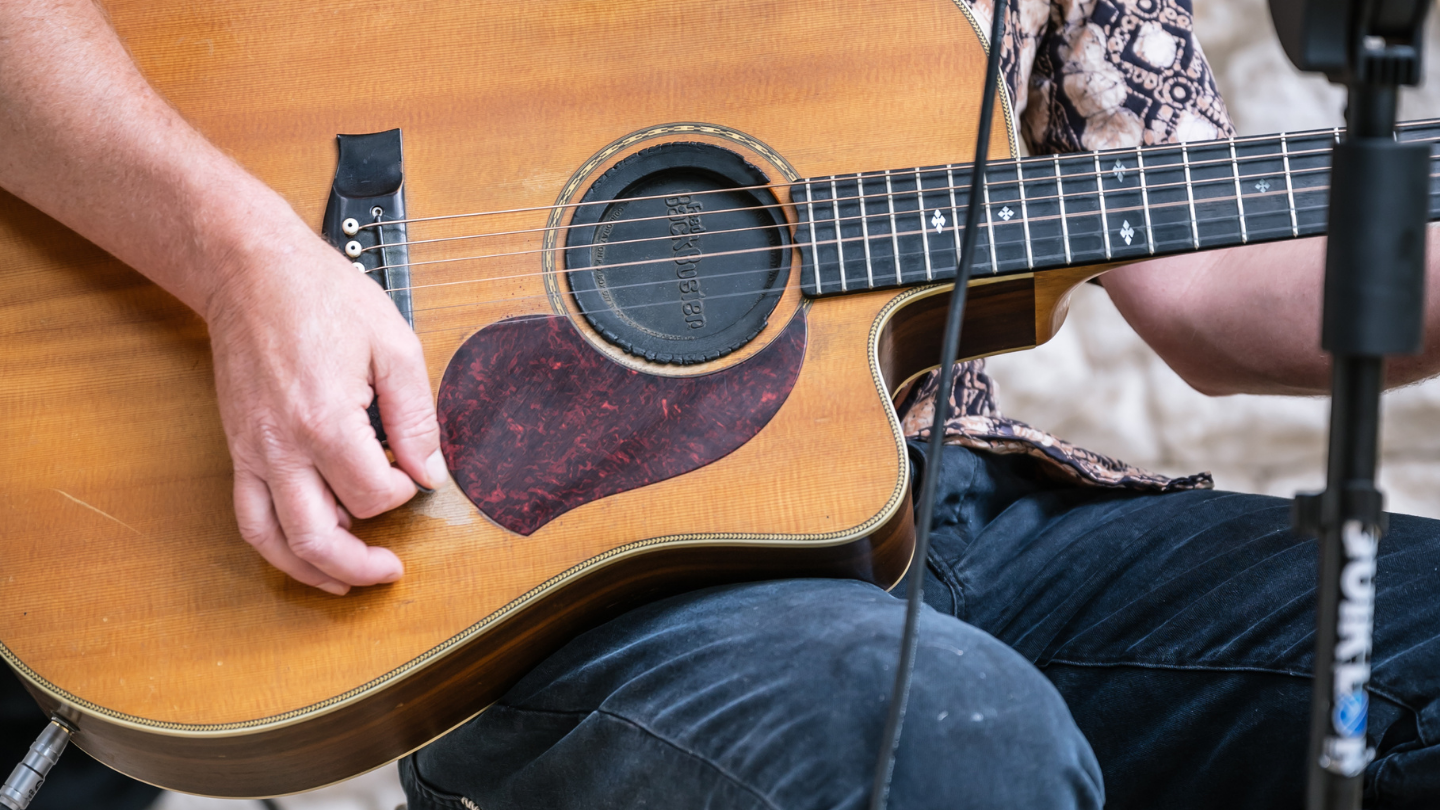 close up of man playing guitar on his lap