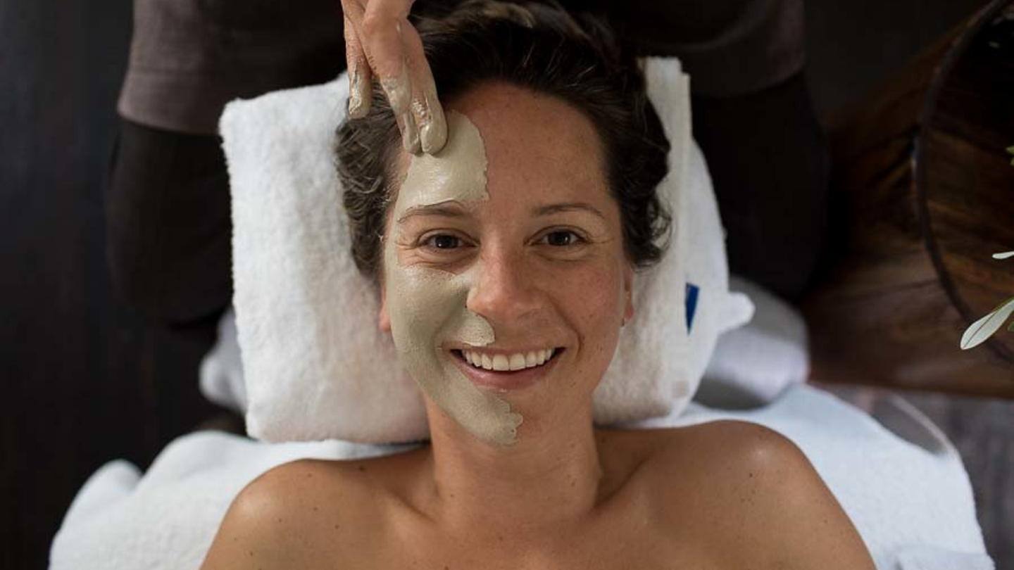 overhead shot of girl smiling to the camera whilst getting a clay facial