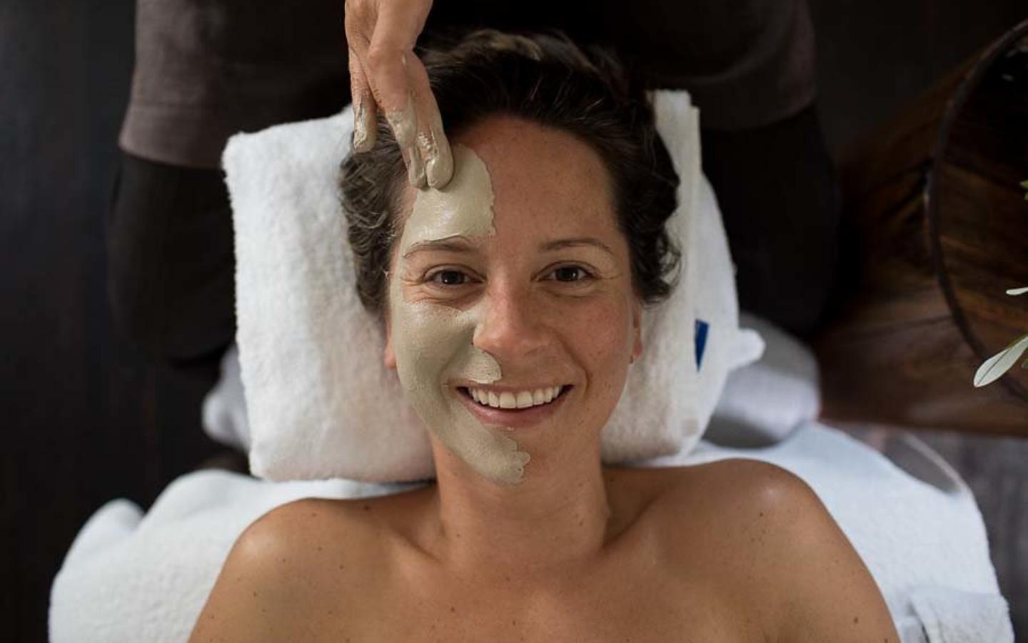 overhead shot of girl smiling to the camera whilst getting a clay facial
