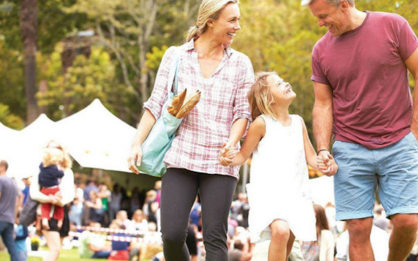 a couple holding hands with a child walking through the market