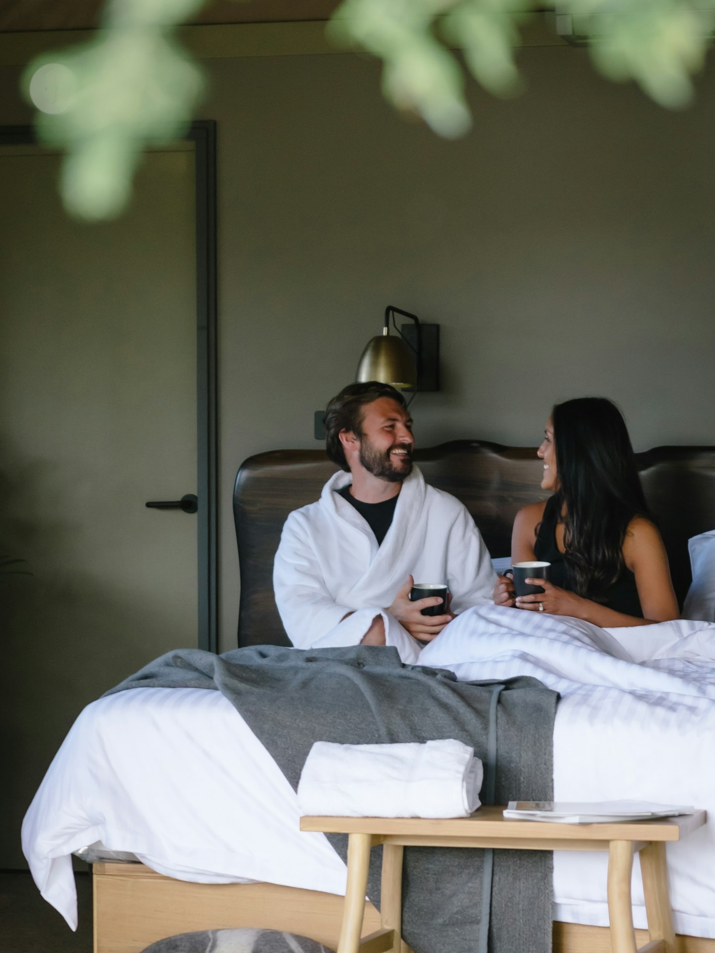 man and woman sitting up in bed chatting over cups of tea