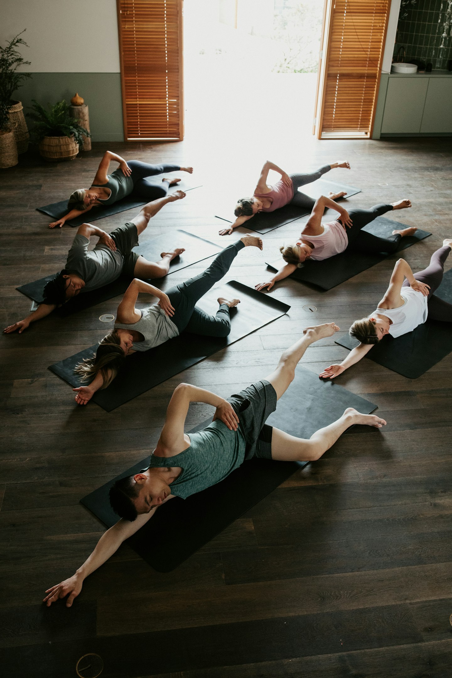 group of seven adults on yoga mats doing Pilates in indoor space