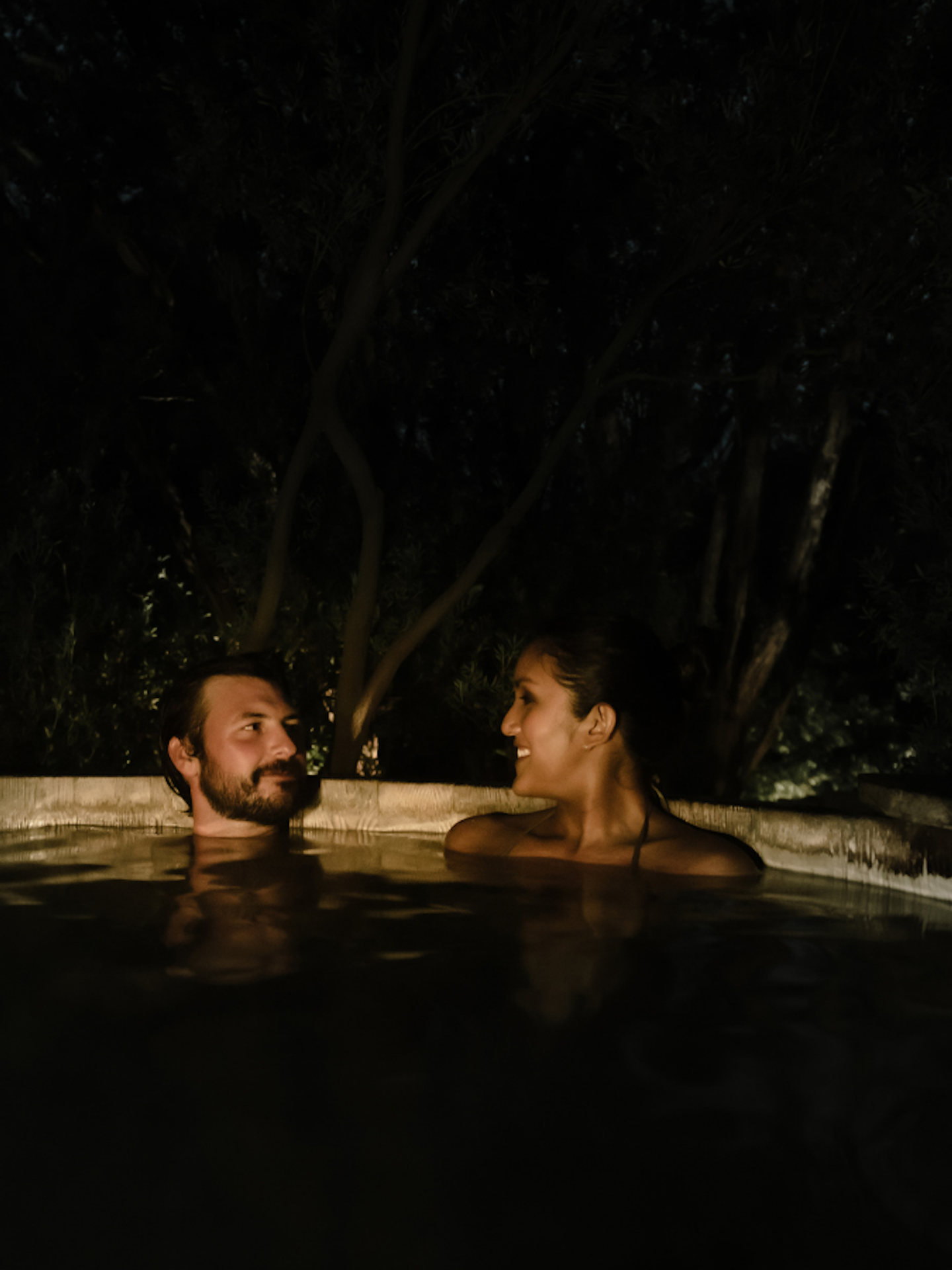 a couple soaking at night in the geothermal waters