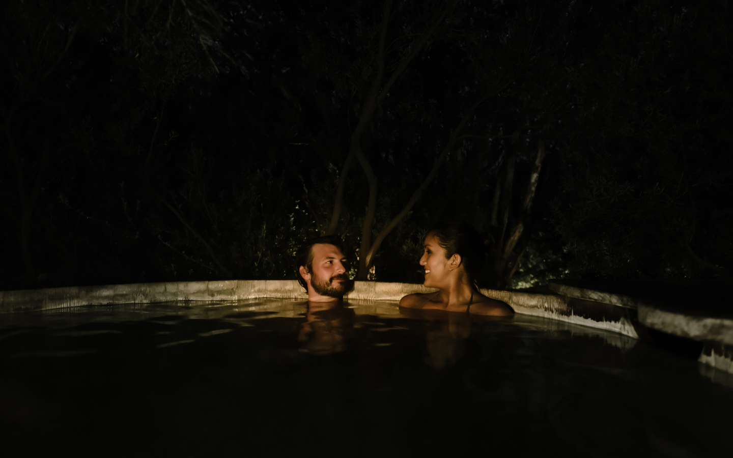 a couple soaking at night in the geothermal waters