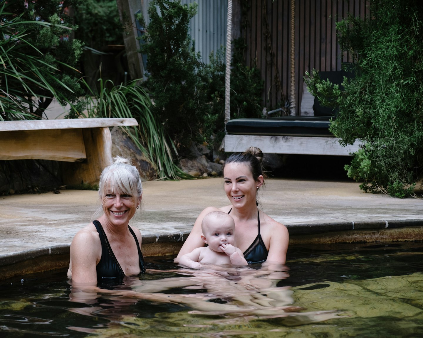 woman with her mum and her baby sitting in geothermal pool
