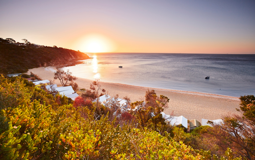 a beach at sunset with beach houses in view