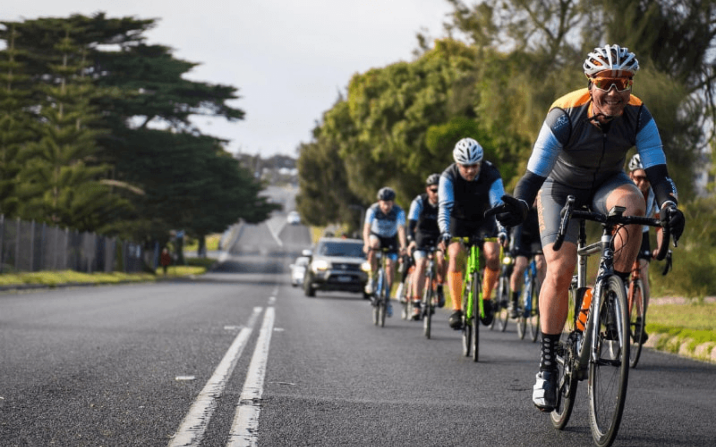a group of riders riding their bike on the road