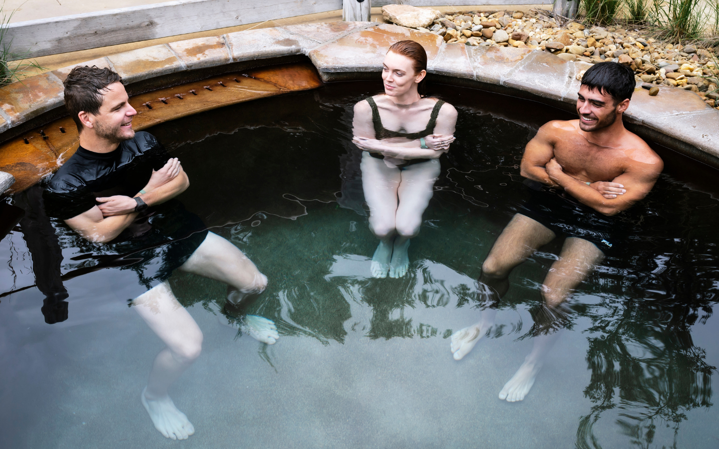 two men and a woman in a cold pool with their arms crossed