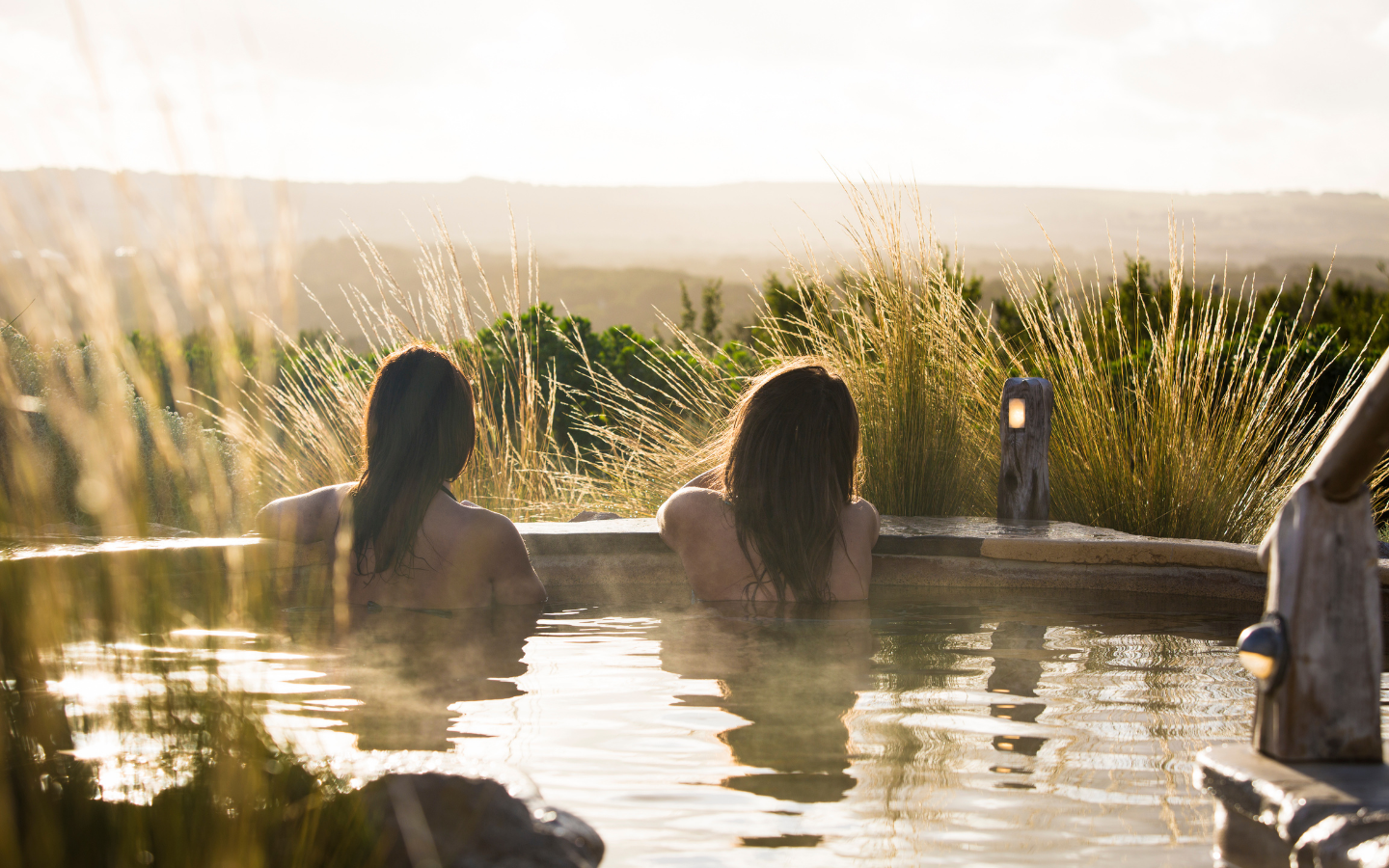 two women relaxing in hilltop pool looking out at view
