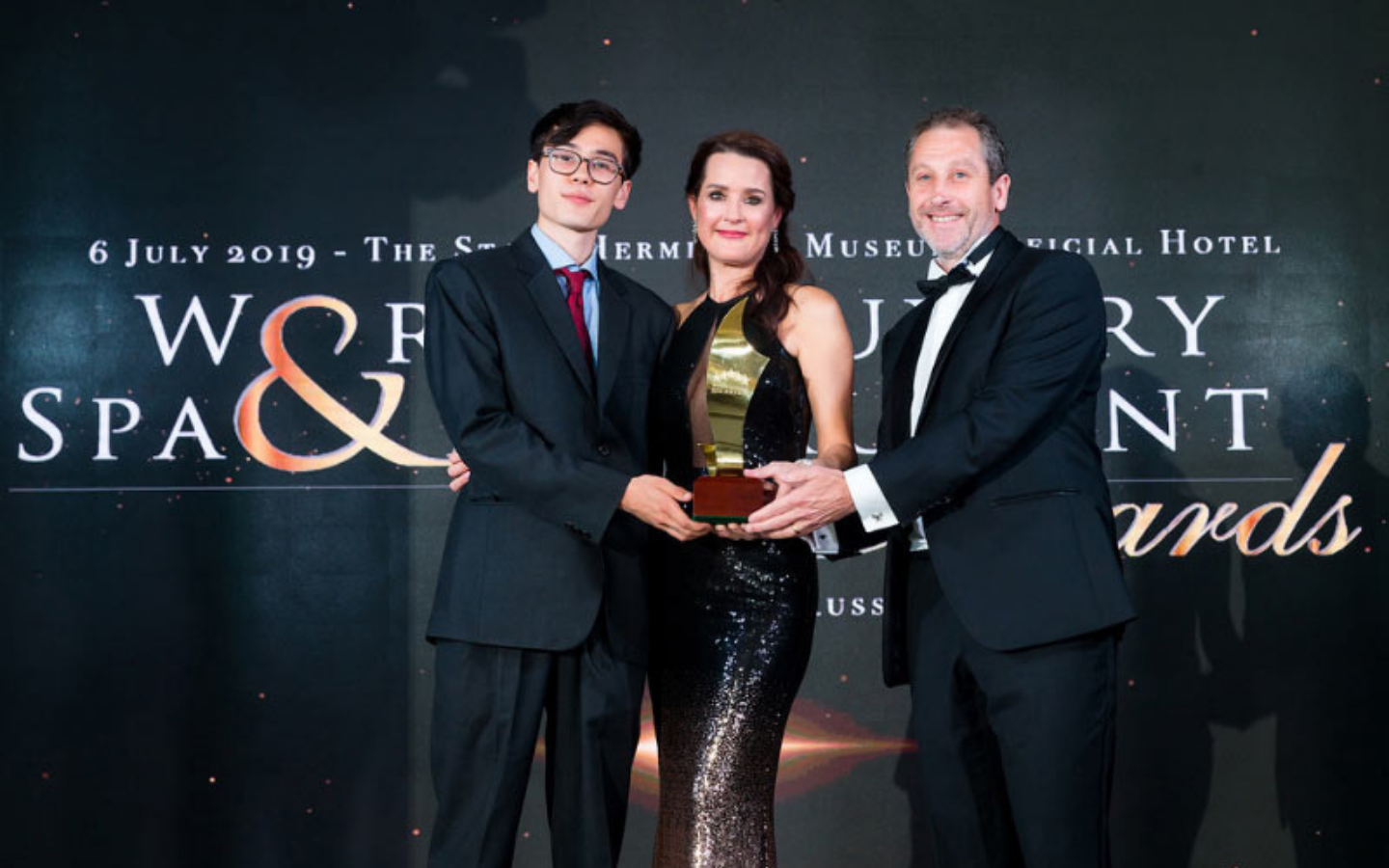 two men and a woman holding an award