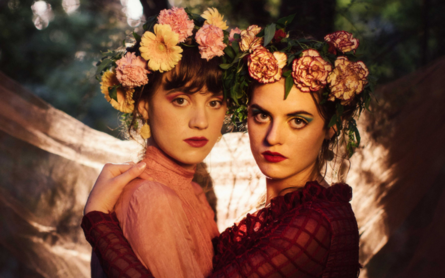two girls in colour hugging and looking at camera