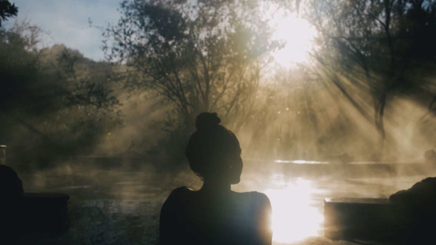 girl sitting in bath with sun shining and steam off pool