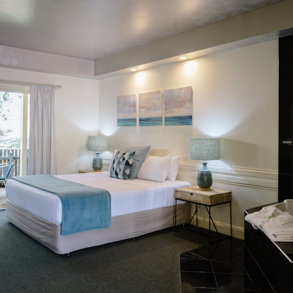 a queen bed with blue runner in large room with bath