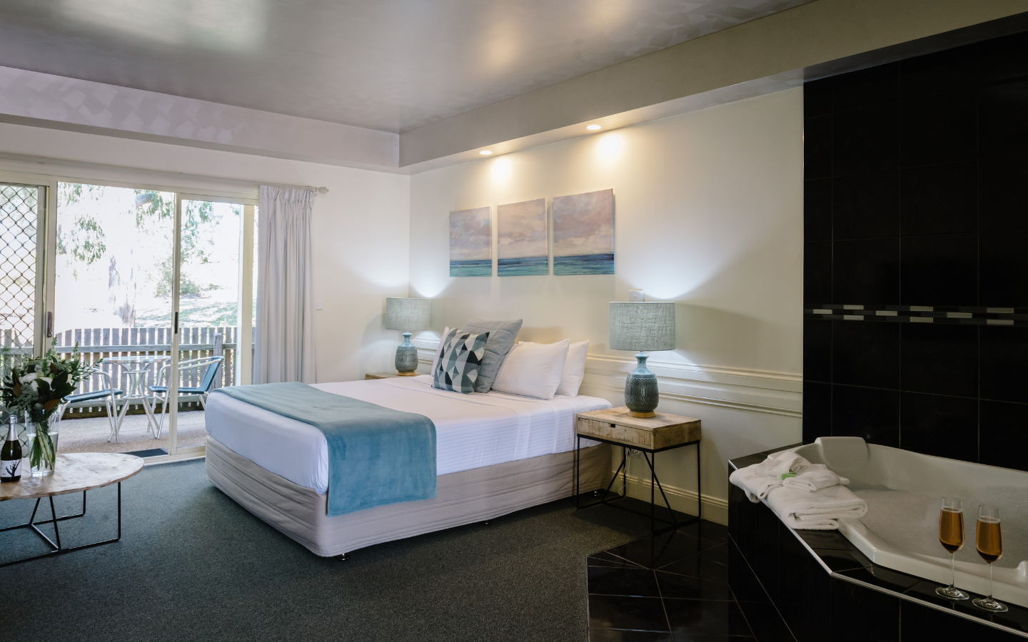 a queen bed with blue runner in large room with bath