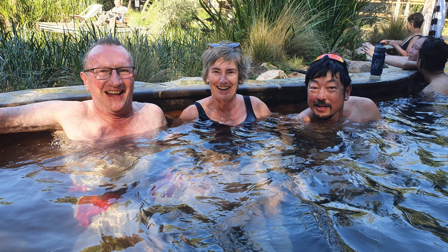 three people soaking in a geothermal bath