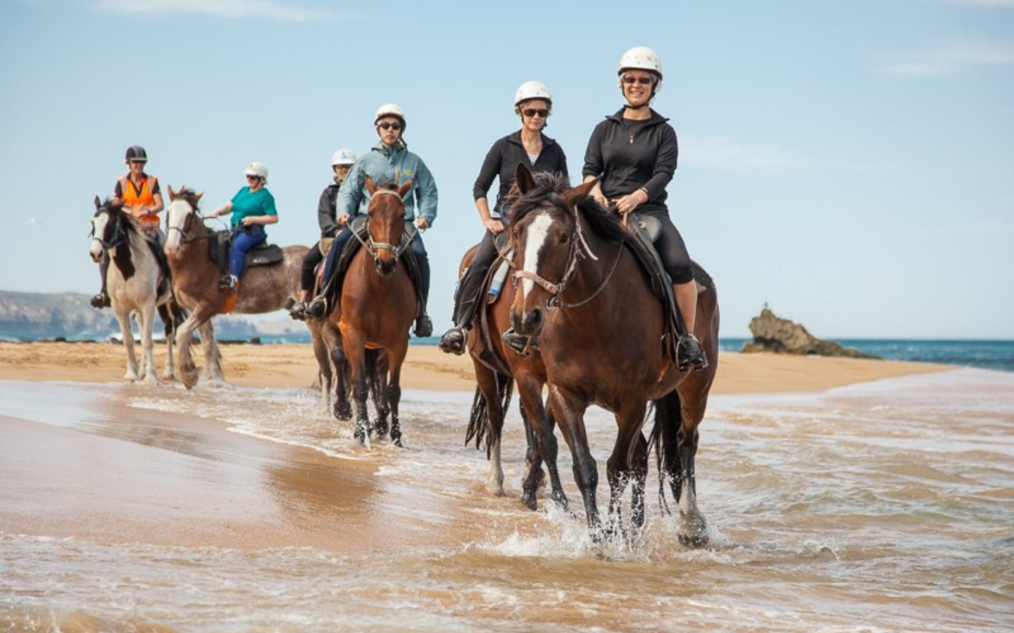 a group of people on horses on a beach