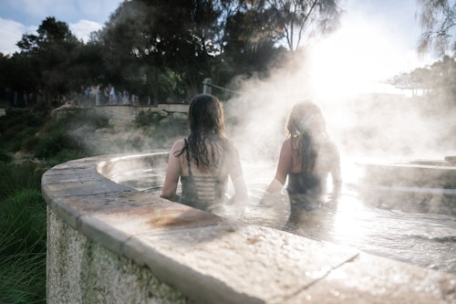 two girls walking in a pool with steam