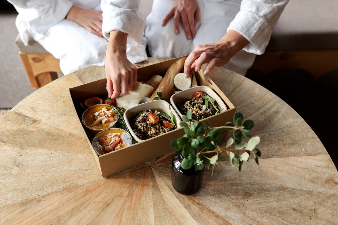 two people grabbing food from a picnic hamper