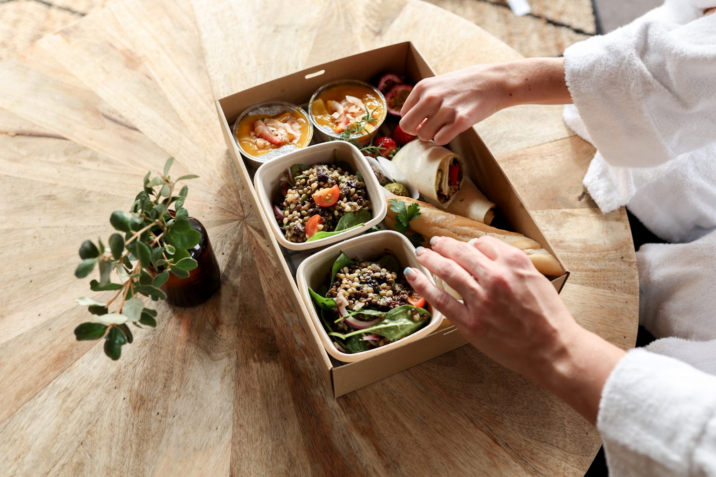 two people grabbing food from a picnic hamper