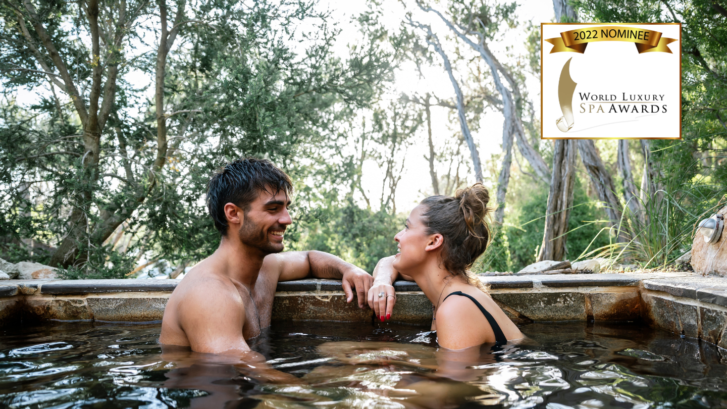 a man and a woman in a pool with the world luxury spa awards logo in the top right corner