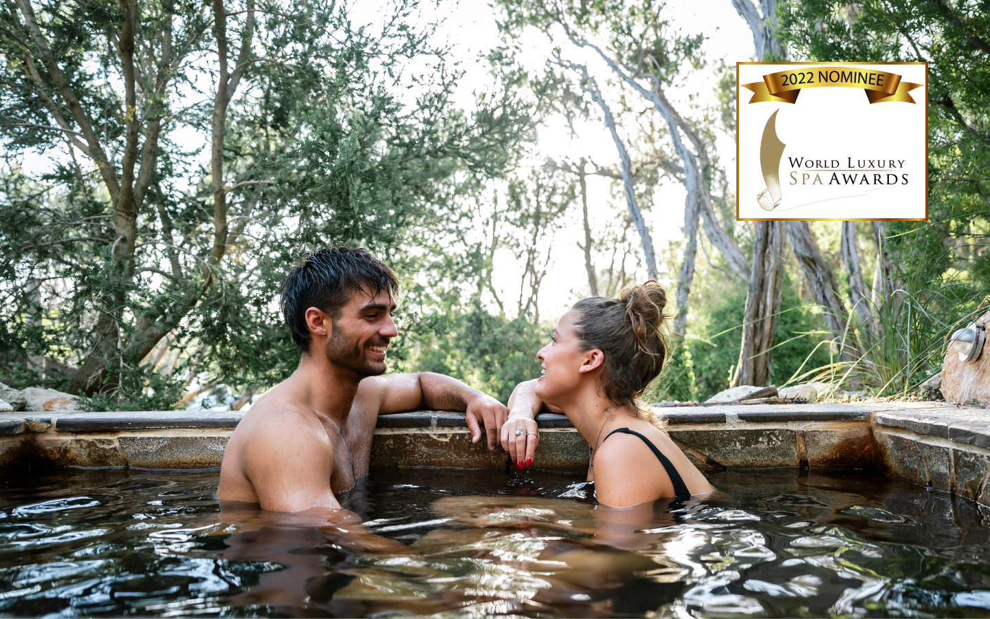 a man and a woman in a pool with the world luxury spa awards logo in the top right corner
