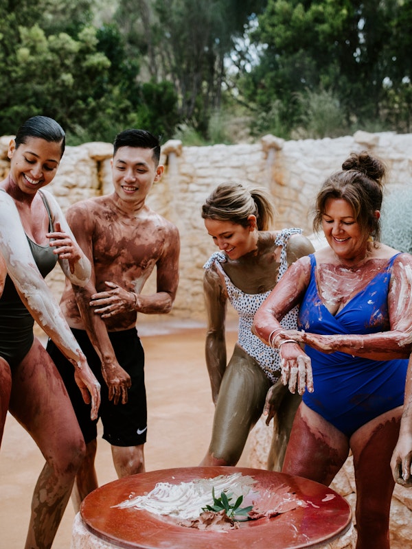 a group of people rubbing body clay on their bodies