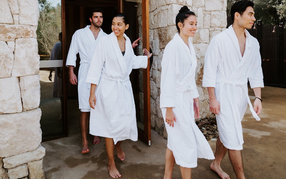 a group of people in robes walking out of a sauna