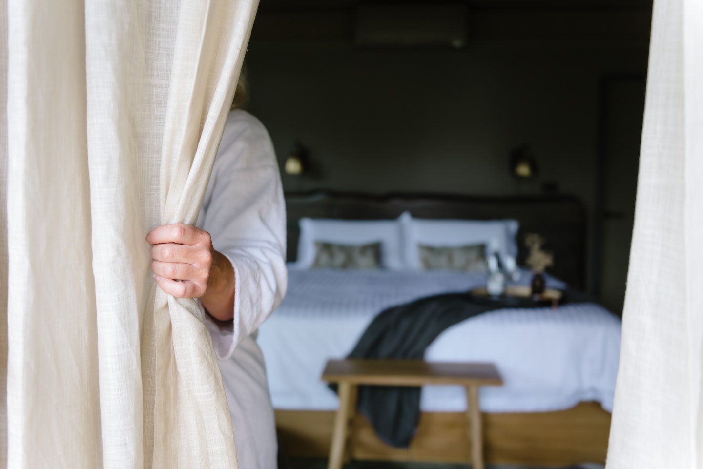 a curtain peaking open to the sight of a bed