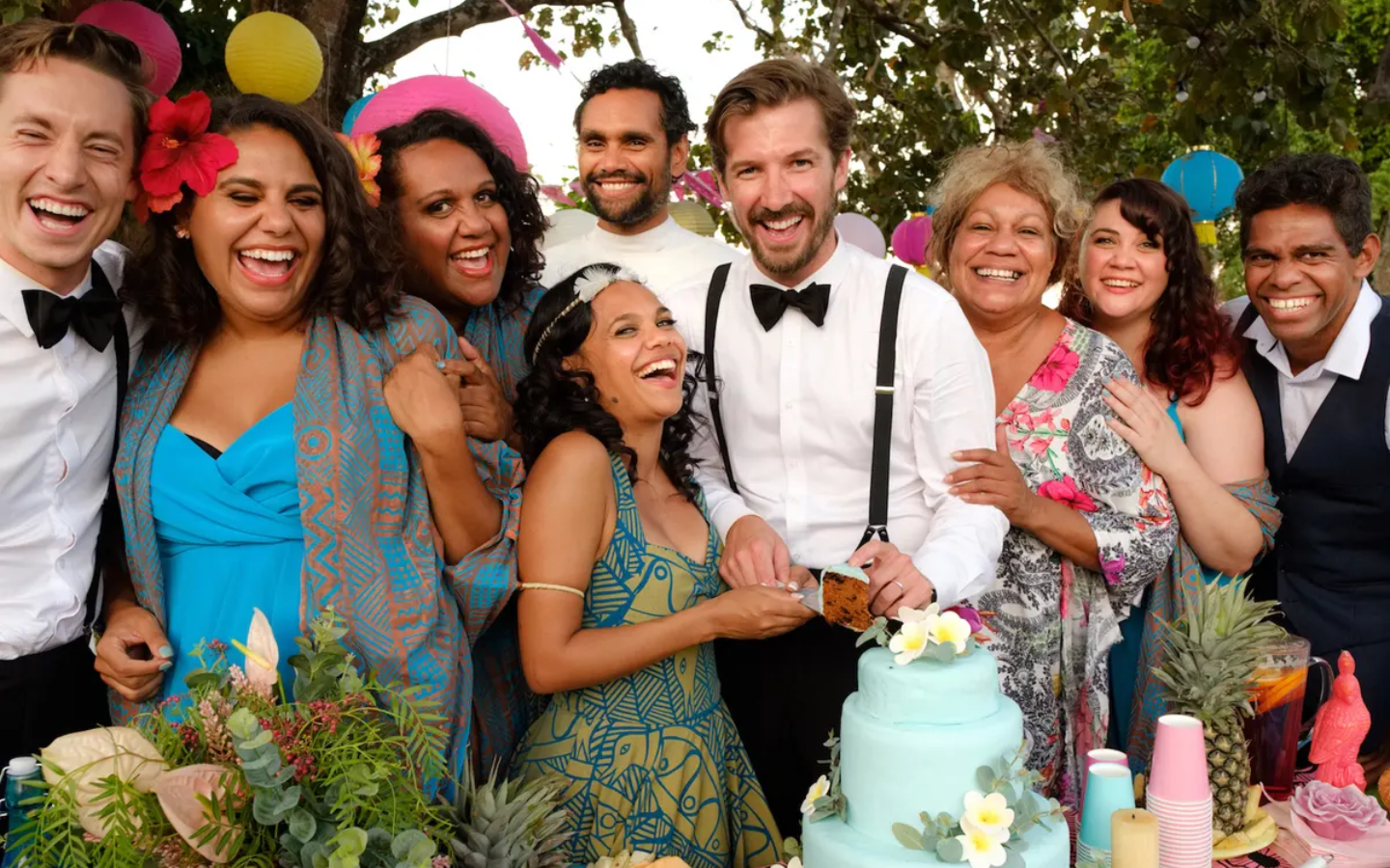a group of people standing in front of a cake