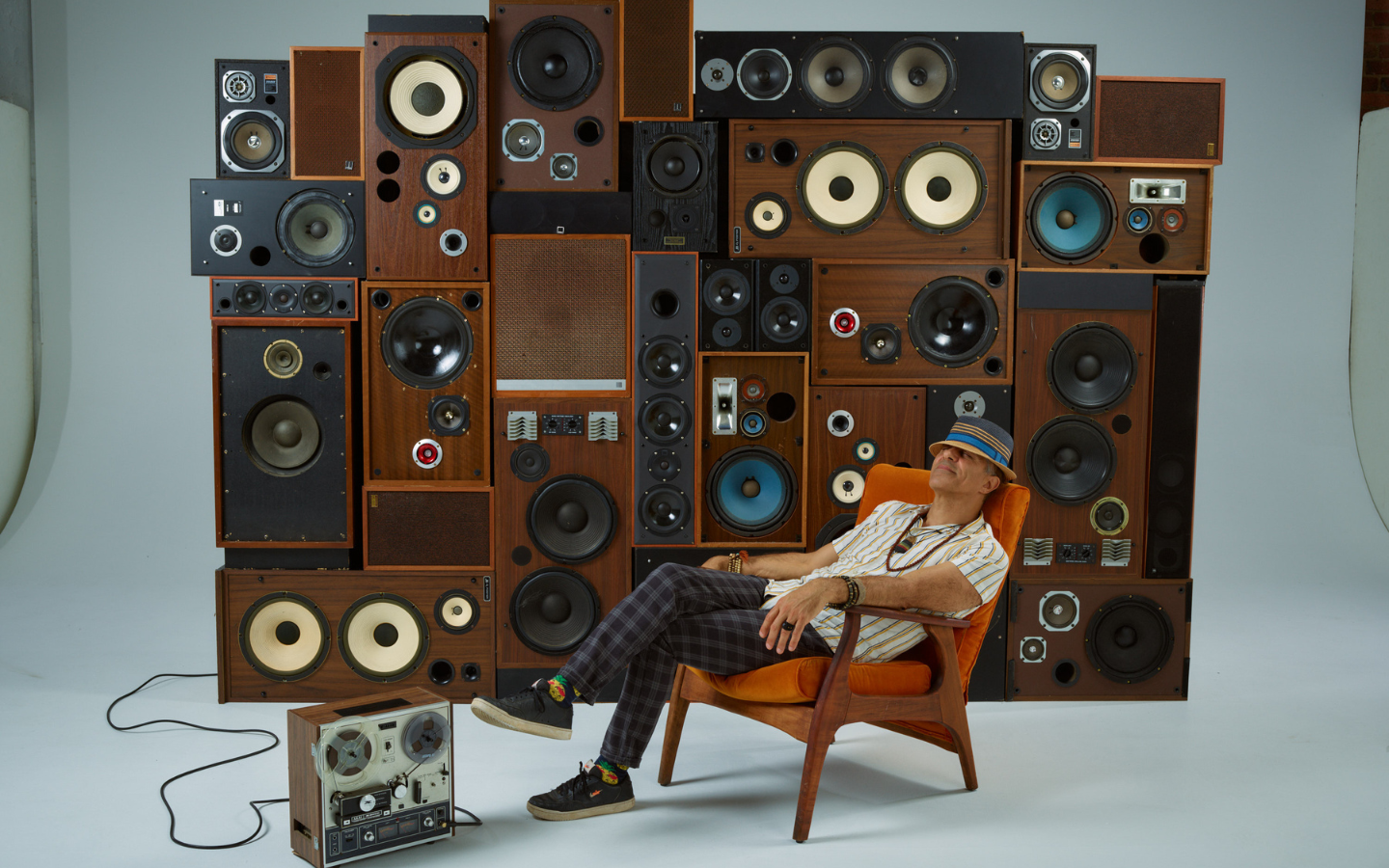 a man sitting in front of a wall of stereos
