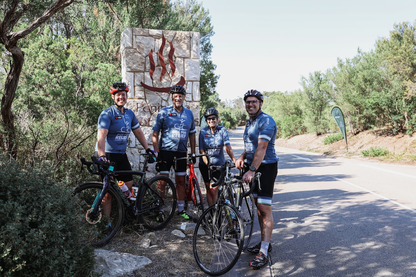 a group of people with bikes smiling in front of an onsen sign