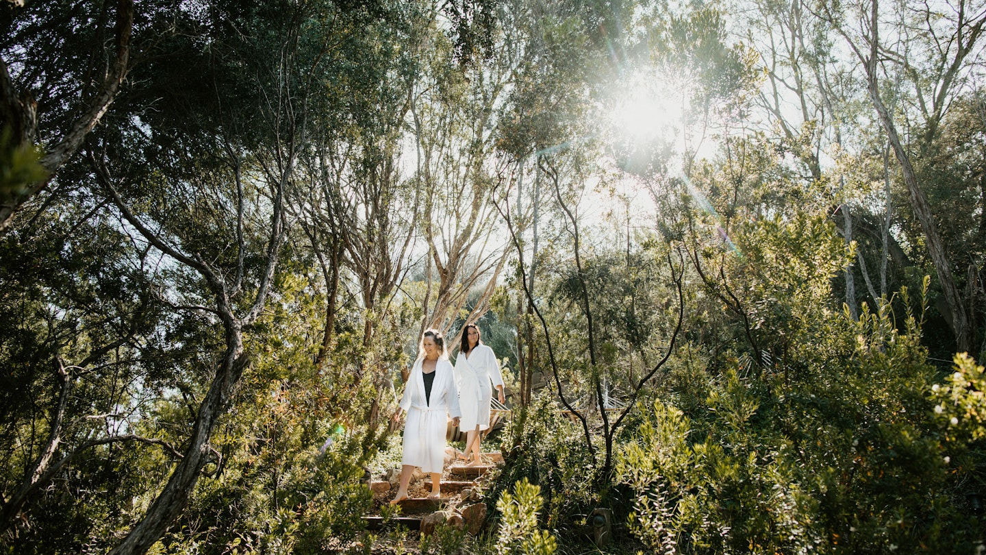 two women walking through nature in white robes