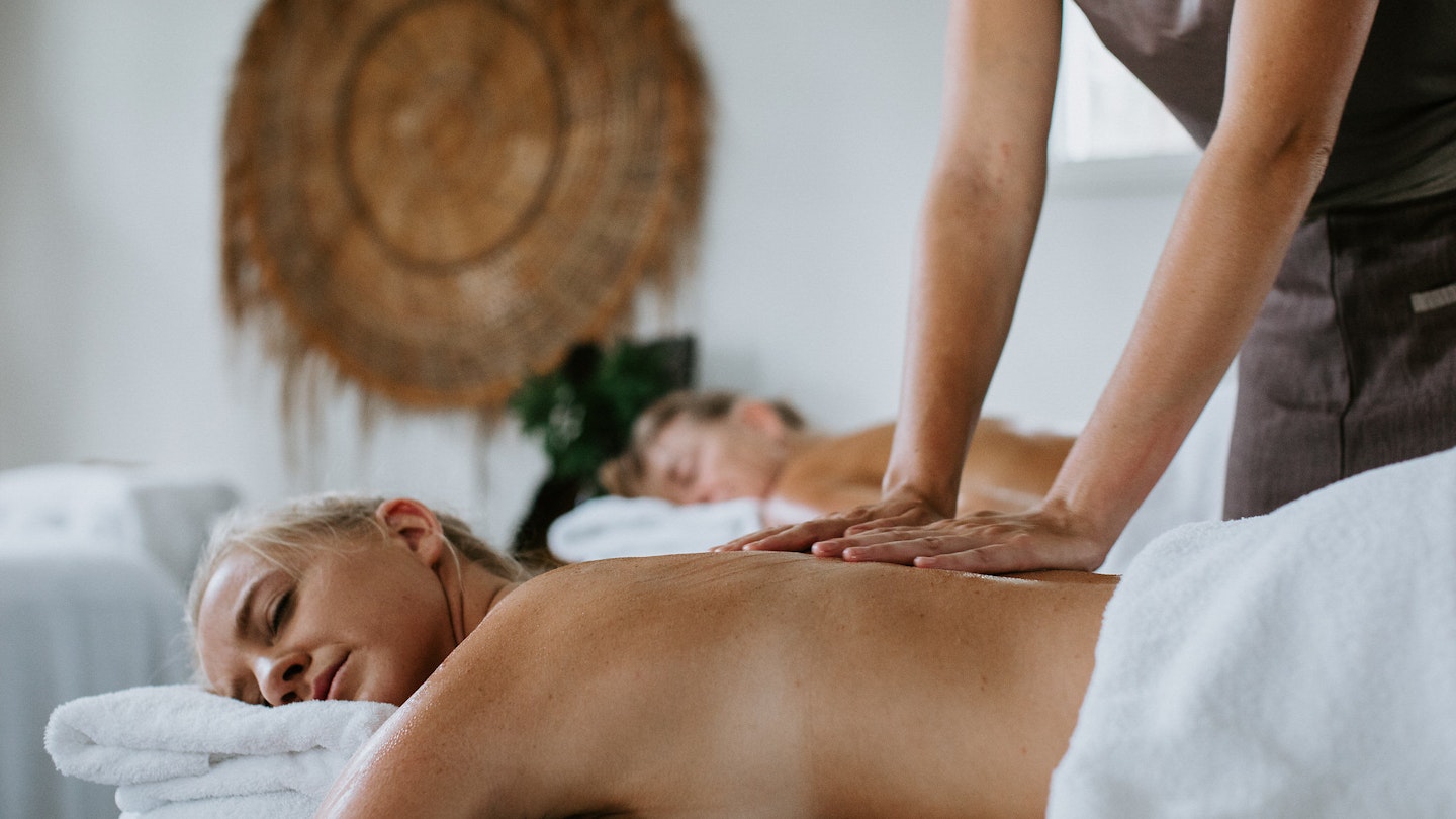 a women lying on a bed getting a back massage