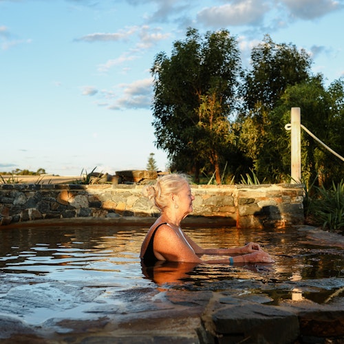 a woman sitting in a pool at sunset