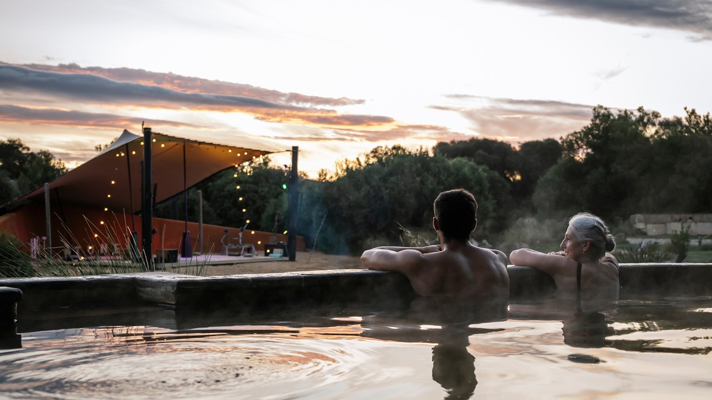 a man and woman sitting in a pool looking at the stage