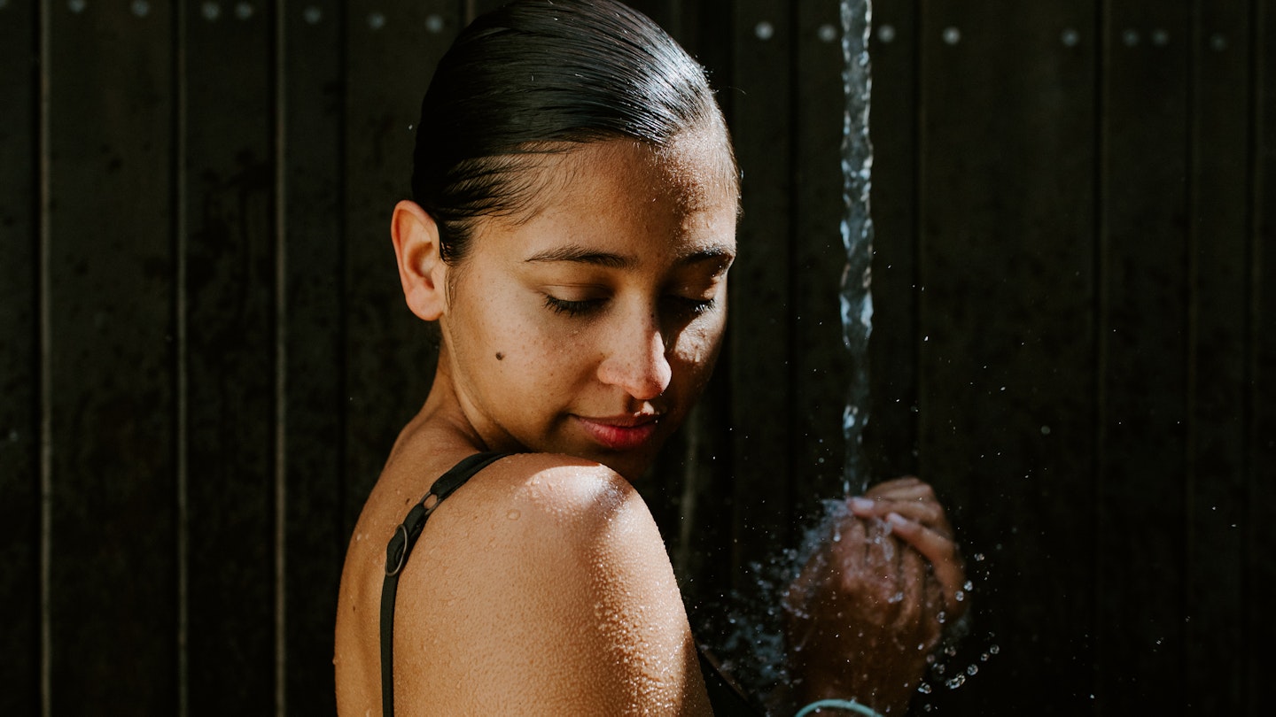 A woman standing under a flowing shower