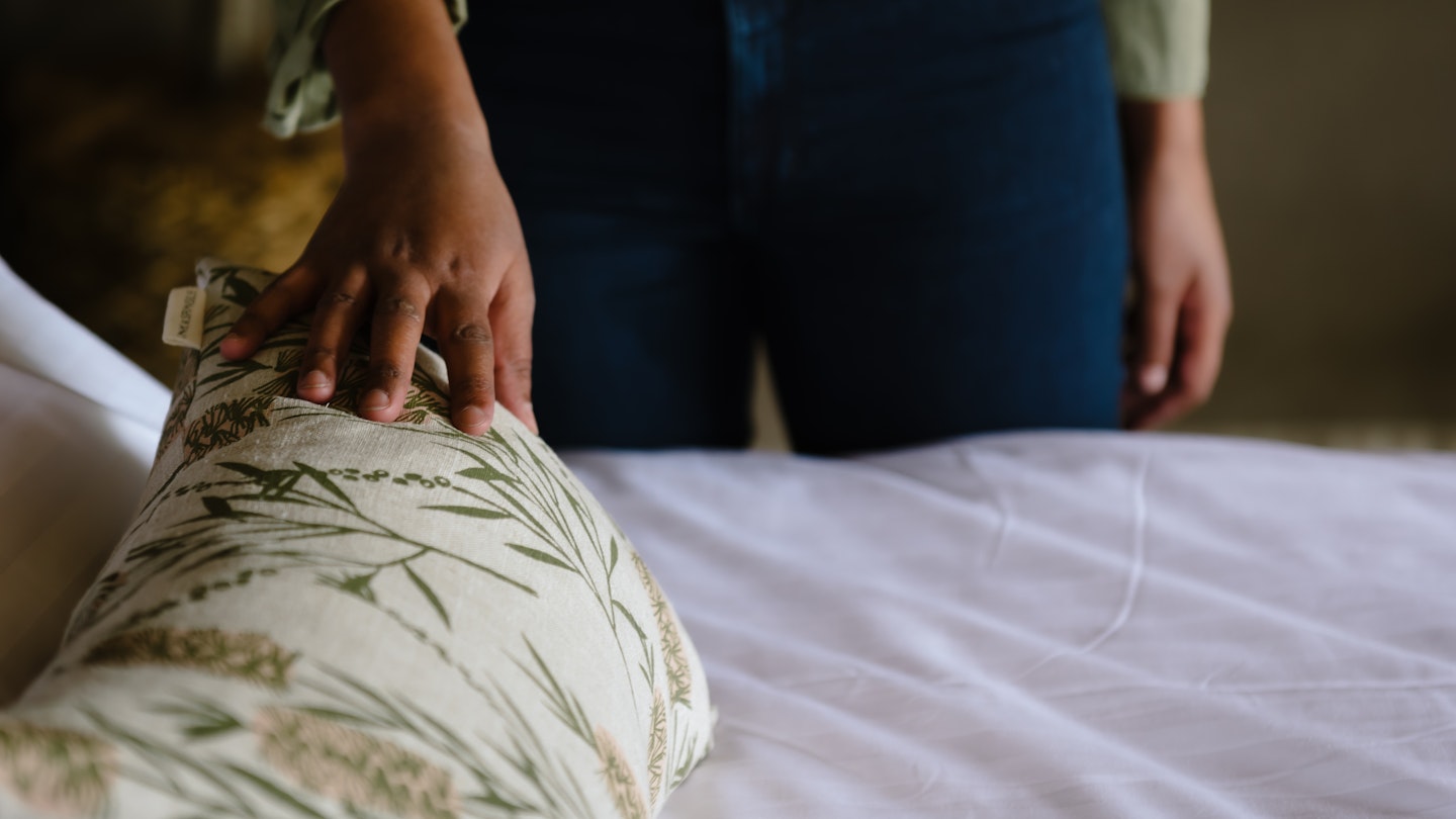 A woman stroking a floral cushion on a bed