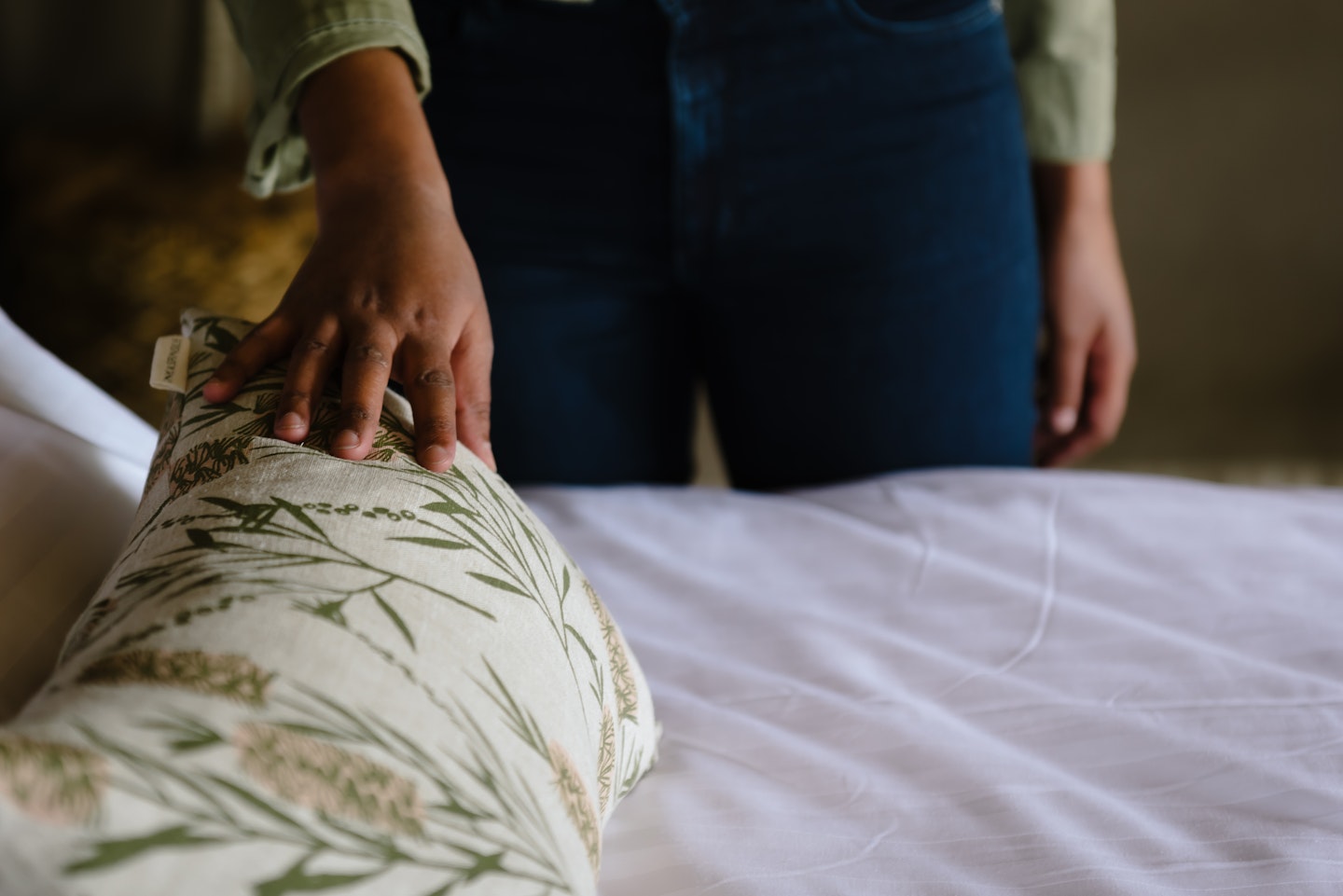 A woman stroking a floral cushion on a bed
